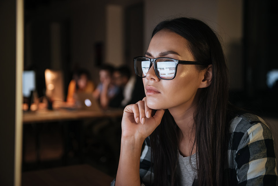 Woman wearing glasses in front of a computer