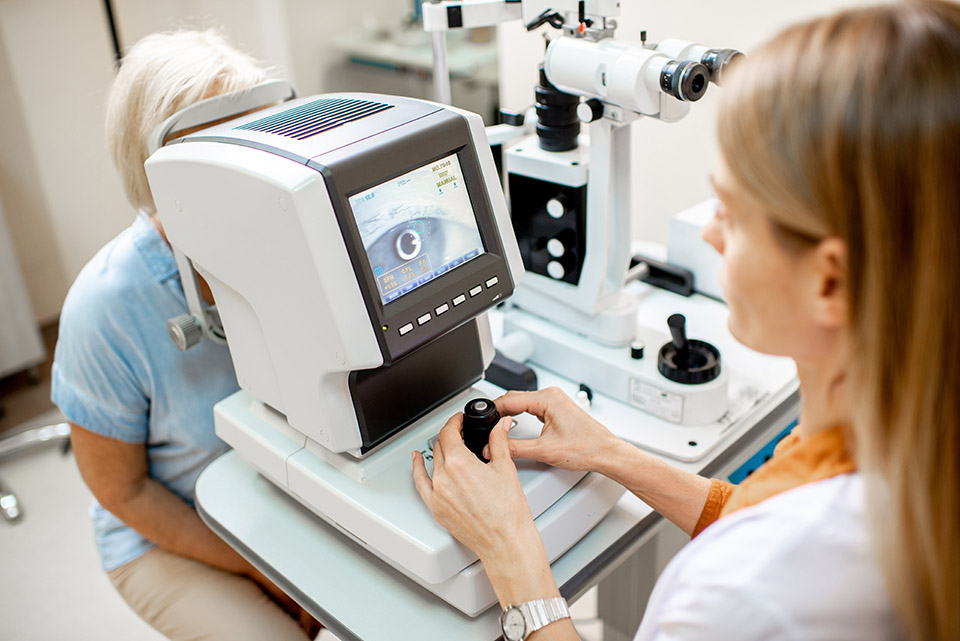Ophthalmologist examining eyes of a senior patient using digital